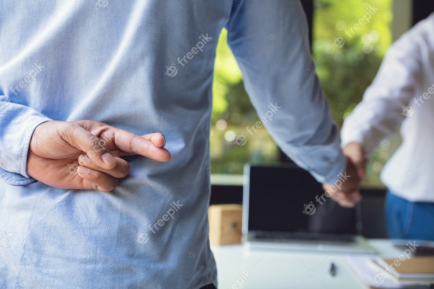 Trickery concept.business partners shaking hands with one of them holding fingers crossed behind back. Premium Photo
